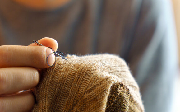 Mending clothes. Repairing woolen sweaters, shopping less concept. Selective focus