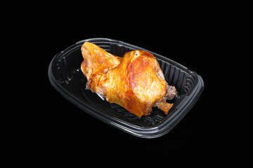 Roasted half chicken in a black package on a black background