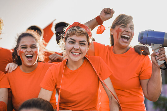 Multiethnic football supporter fans watching soccer match at stadium -  People with orange t-shirts having excited fun on sport world championship event