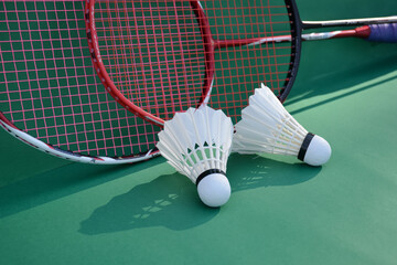 Cream white badminton shuttlecock and racket on floor in indoor badminton court, copy space, soft and selective focus on shuttlecocks.