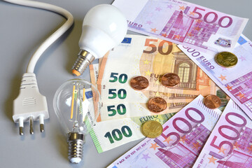 Electric plug, euro money banknotes and cents with light bulb over grey background. Concept for the increase of electricity cost. Expensive energy bill and rise in electricity prices.