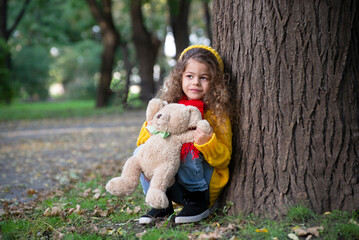 Portrait of a little girl  is playing in the park in autumn