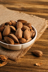 unpeeled almonds in a shell in a bowl, on a wooden table