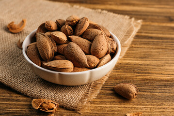 unpeeled almonds in a shell in a bowl, on a wooden table