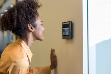 Woman using face scanner to unlock door in office building. Access control facial recognition...