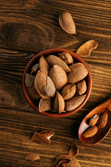 unpeeled almonds in a shell in a bowl, on a wooden table