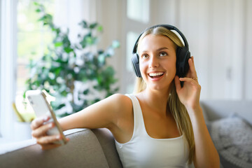 Relaxed teen girl wearing earphones listening to mobile music playing via smartphone app