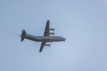 Four-engined turboprop transport aircraft is in blue sky