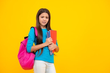 Back to school. Teenager schoolgirl hold book and copybook ready to learn. School children on isolated yellow studio background. Angry face, upset emotions of teenager girl.