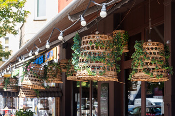 Wicker lampshades in an outdoor street cafe. Decorating hanging lantern lamps in wooden wicker made from bamboo. Vintage asian restaurant decorations