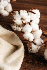 
a branch of natural cotton on a wooden table with a white cloth