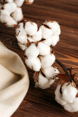 
a branch of natural cotton on a wooden table with a white cloth