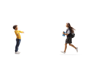 Full length profile shot of a schoolgirl running towards her little brother