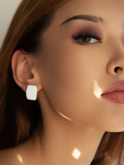 beauty, jewelry, accessories, people and luxury concept - beautiful asian woman with earring over...