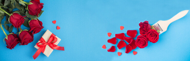 Holiday banner. Gift box and paintbrush with red roses and hearts on the blue background. Top view. Copy space.