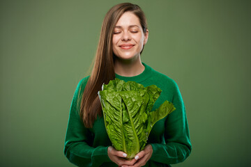 Smiling woman with eyes closed holding romaine lettuce salad. Advertising female portrait on green.