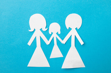 Same sex couple adoption concept. Paper dolls two mothers holding hands of offspring on blue...