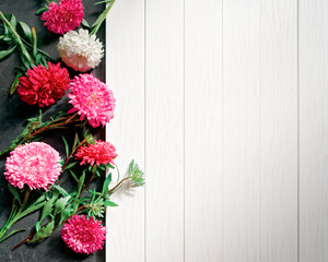 A bouquet of red, pink, white asters and dry eucalyptus branches is on a white wooden background. Abstract autumn composition with copy space.