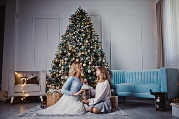 Mother and daughter at home near the Christmas tree. Winter holidays. Studio photo.