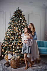 Mother and daughter at home near the Christmas tree. Winter holidays. Studio photo.