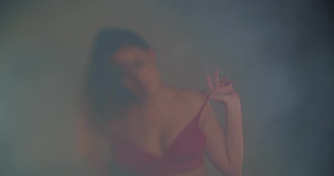Beautiful girl dancing in bra and jeans, selective focus, smokey scene