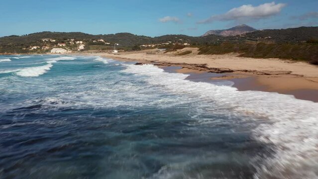 Pero beach of Cargese in Corsica on a sunny day. Drone aerial view of the Mediterranean Sea and sand beach with rocks at sunrise