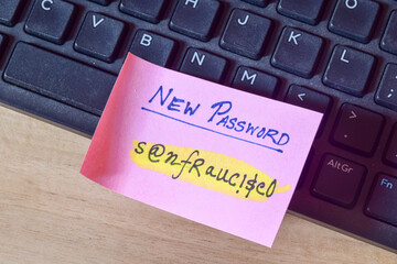 Strong password setting concept for cybersecurity. Sticky note with the new password containing alphanumeric characters on keyboard. 