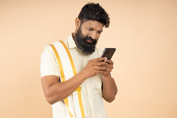 South Indian man Wearing Traditional White outfit using mobile phone, 