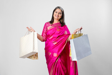 Indian older woman in traditional saree and holding shopping bag