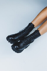 Young woman in black stylish fashion leather lace-up shoes standing on white tile. Fashionable collection of women's autumn shoes. Close-up of female legs in shoes.