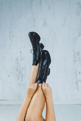 Female legs in leather black autumn boots. A fashion girl stands in a store and measures shoes.