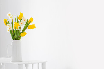 white and yellow spring flowers  in vase on white background