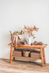A wooden bench, a basket with plaid, autumn leaves in a ceramic vase - a cozy autumn interior