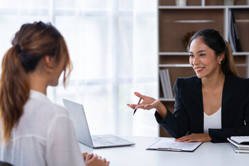Fototapeta premium The collaborative process of young Asian business people team sitting and working with tablets together discussing, researching, brainstorming, and planning work in the office