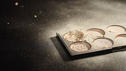 Close up view of palette with crushed face powder on black background