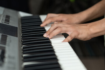 Teenager's hands on the keys of an electronic piano instrument, selective focus, the concept of music school classes