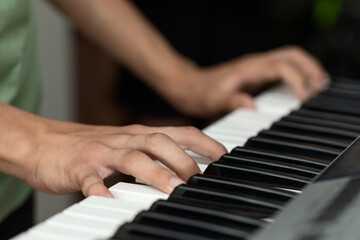 Fototapeta na wymiar Teenager's hands on the keys of an electronic piano instrument, selective focus, the concept of music school classes
