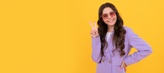 teen girl in stylish purple jacket and sunglasses on yellow background show peace gesture. Child face, horizontal poster, teenager girl isolated portrait, banner with copy space.