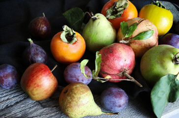 Varietà di frutta autunnale su sfondo scuro.