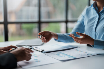 Business people meeting to plan the financial market looking at past quarterly company graph and chart to compare investment and analyze company revenue and marketing strategy.