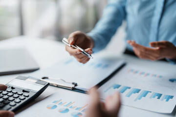 Business people meeting to plan the financial market looking at past quarterly company graph and chart to compare investment and analyze company revenue and marketing strategy.