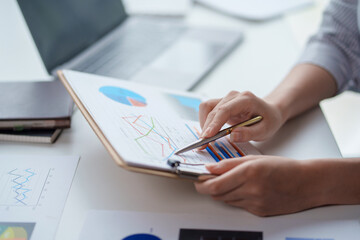 Close-up of businesswoman hands working and pointing to a chart expenses, manage budget, income tax, budget, documents, credit documents, invoices.