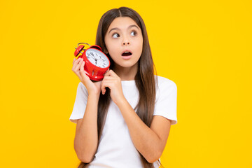 Teen student girl with clock isolated on yellow background. Child back to school. Education and time concept. Amazed surprised emotions of young teenager girl.