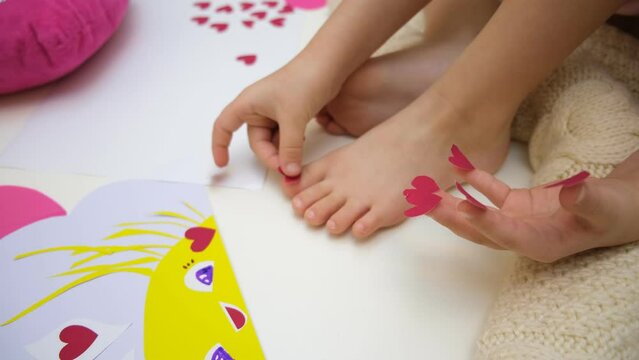 Child playing with adhesive tape paper , making funny card with sun and hearts	
