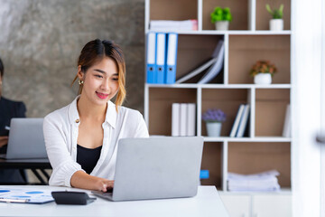 Attractive and confident, successful Asian businesswoman sitting on her laptop in the office.