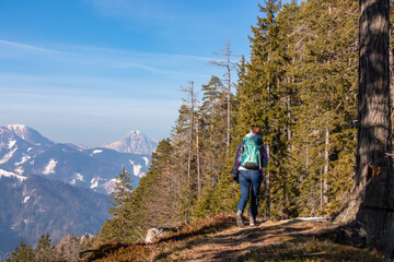 Woman on hiking path in winter near Zell Pfarre towards Freiberg, Austrian Alps, Carinthia (Kaernten), Austria, Europe. Scenic view from forest on snow capped mountain peaks of Karawanks, Julian Alps