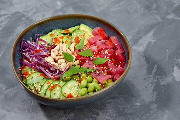 Top view on poke salad with tuna and green vegetable in the bowls on gray background. Copy space.