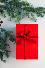 Fototapeta na wymiar Christmas tree branch with red gift box on white background. Minimal creative flat lay. New Year Christmas background concept.