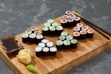 Top view background with set of colorful different kinds of sushi rolls placed on wooden board