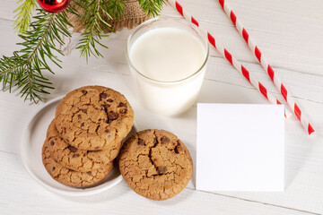 Christmas traditional milk for Santa with straws, cookies, empty blank note on white wooden table.